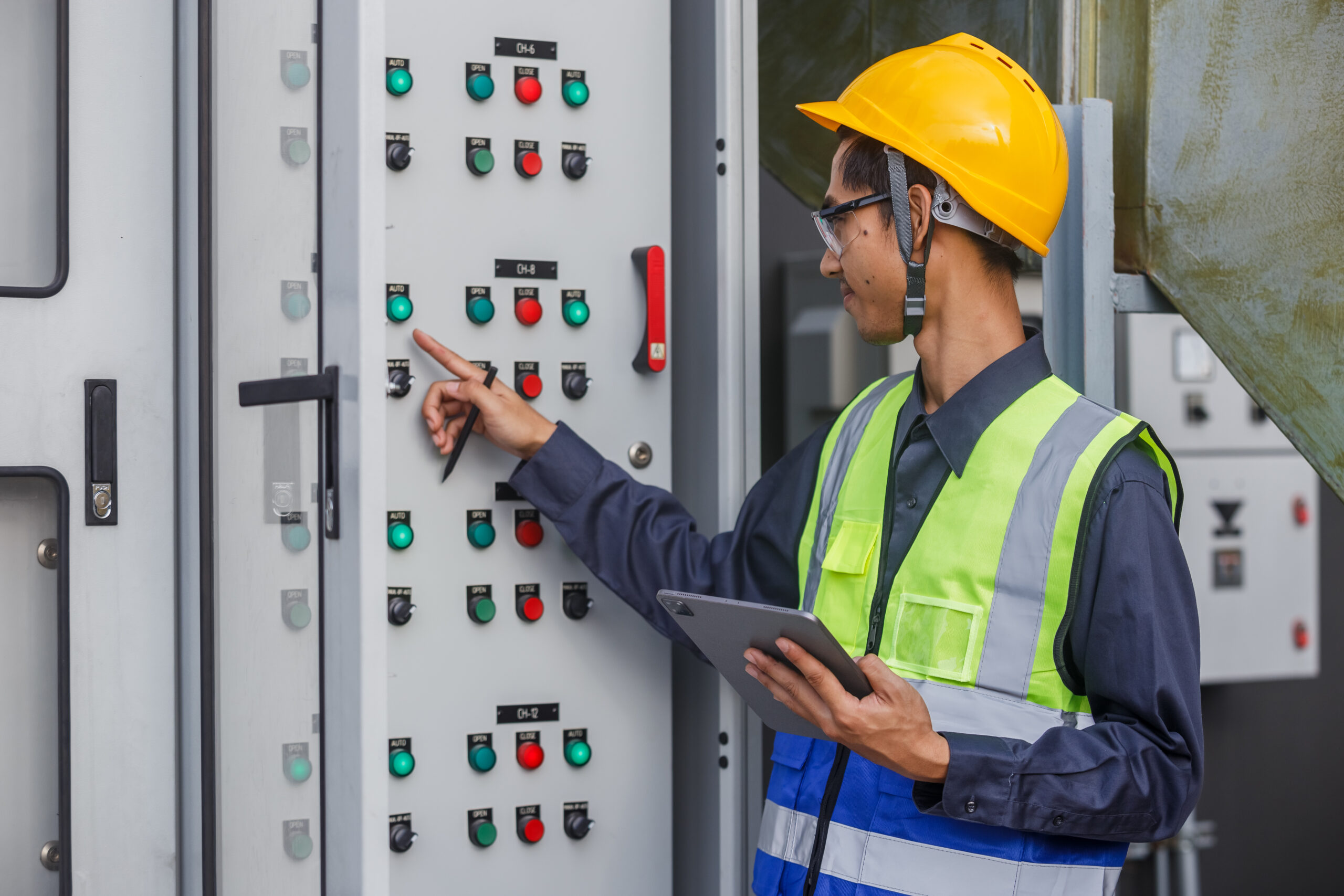 Electrical engineer man using tablet checks switchboard main Dis